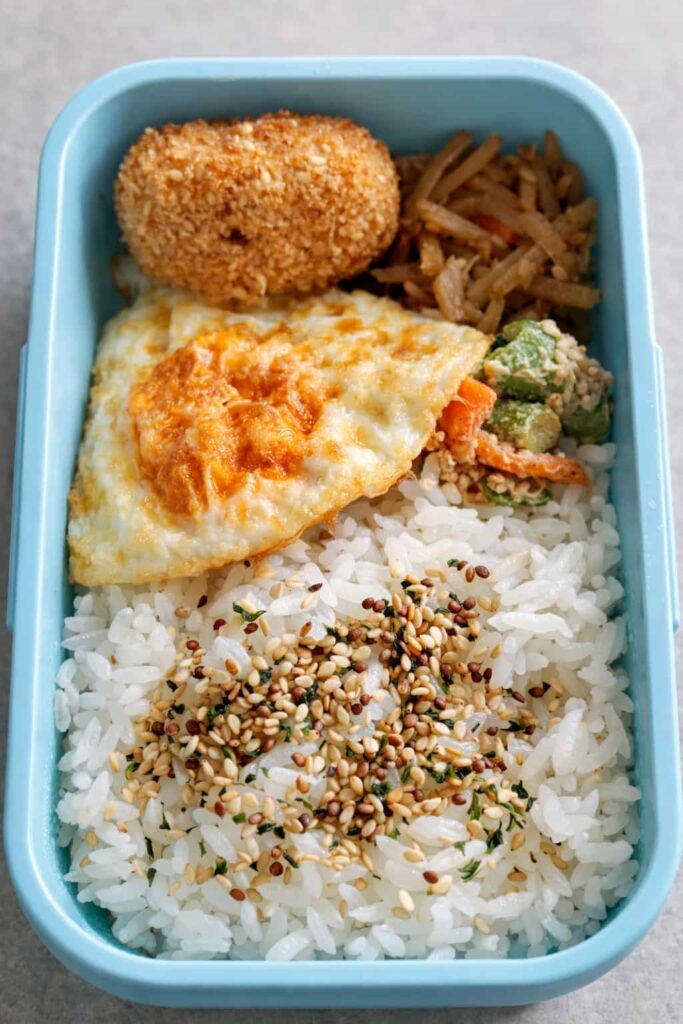 揚げ物、目玉焼き、副菜が入っているお弁当の写真。